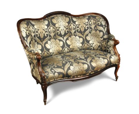 A mid-Victorian rosewood framed sofa, with a shaped back and carved scroll arms and foliate carved show wood, upholstered in 