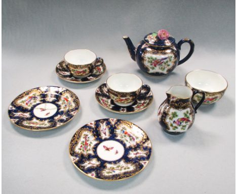 A Royal Worcester tea service for two, decorated in 18th century style, the blue scale body reserved with shaped panels, pain