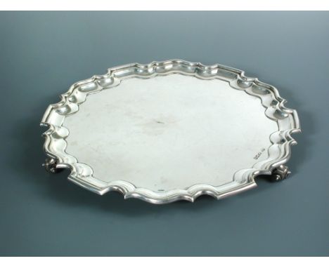 A circular silver salver, by Walker and Hall, Sheffield 1954, 'Chippendale' style, raised on three leaf topped scroll feet, s