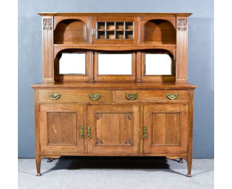 A Victorian Oak Dresser of Art Nouveau Design, the upper part with moulded cornice fitted with one central shelf enclosed by 