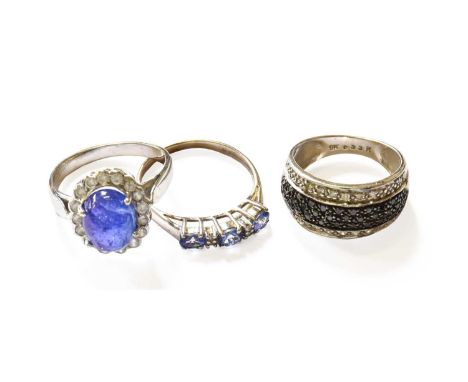 Three Gem-Set Rings, comprising of a black and white diamond half hoop ring, finger size K, a 9 carat gold tanzanite and diam