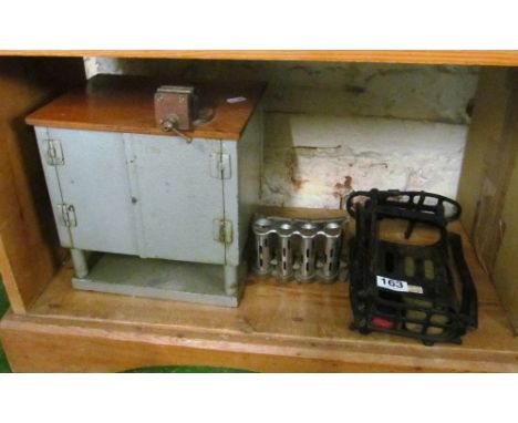 A small metal cabinet with attached vice, an antique shoe shine kit and vintage bus ticket machine