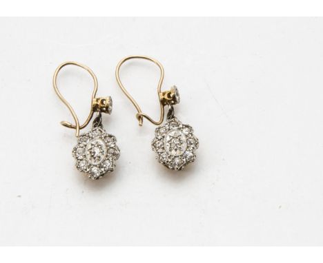 A pair of late 19th century gold and diamond pendant earrings, the hook backs with single stone mount supporting an oval drop