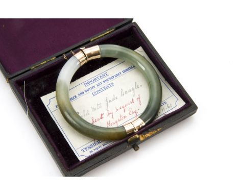 A vintage Chinese jadeite bangle, two semi circles of green hardstone with gold mounts marked 9ct, in box with note from Tess