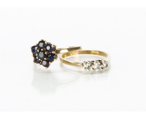 Two 9ct gold and gem set rings, one a three stone diamond example, the other with dark blue sapphires, 3.7g (2) 