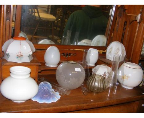 An assortment of glass light shades and oil lamp chimneys