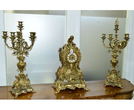 A 20TH CENTURY NEO-ROCCOCO STYLE GILT METAL CLOCK GARNITURE, the clock with enamel dial and Roman numerals below a cherub fin
