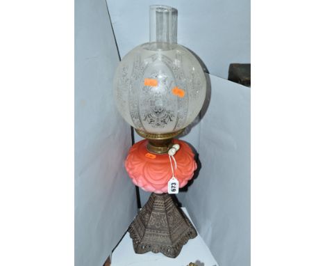 A LATE VICTORIAN OIL LAMP, acid etched glass shade, pink glass reservoir on a hexagonal cast iron base, height to top of chim