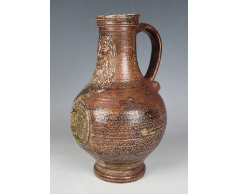 A stoneware Bellarmine jug, probably Rhenish, 17th century, the brown glazed pear shaped body moulded with a smiling bearded 