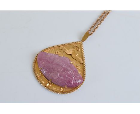 A 9ct gold and carved ruby pear shaped pendant and chain, the central carved oval cabochon ruby decorated with flower heads a