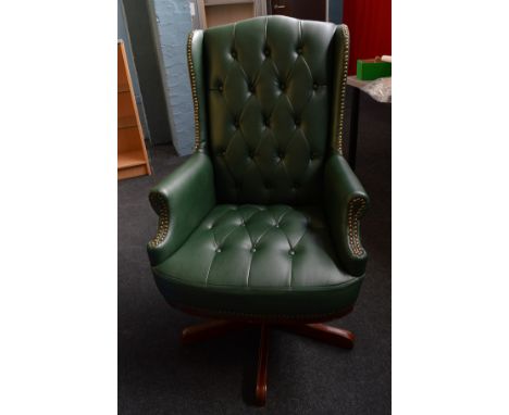 A green leather effect button back swivel desk chair, having studwork to wings and scroll arms on five foot base