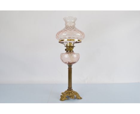 An early 20th century brass and glass oil lamp, brass column support and glass optic moulded reservoir in dusty pink, togethe