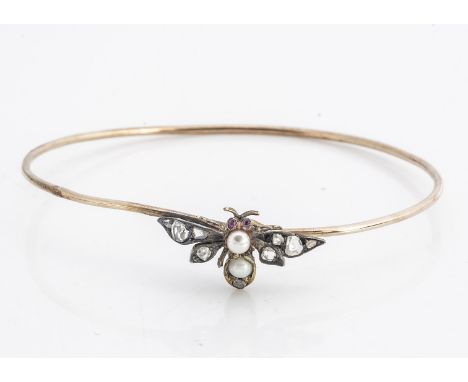An Edwardian gold ruby, diamond and pearl set bangle, the thin oval bangle surmounted with a jewel encrusted bee with pearl s