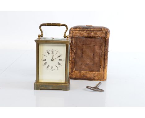 A Edwardian brass cased repeater carriage clock, white enamel dial and roman numerals, in leather case, 18.5 cm high max with