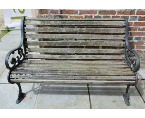 A Wrought Iron and Wooden Garden Bench of shaped form with a slatted seat and pierced end supports, 126 cms wide