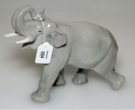 A mid 20th century Russian ceramic model of a bull elephant trumpeting and walking, grey gloss glazed, red printed mark, 22 x