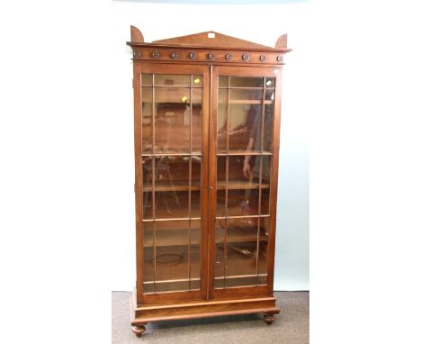 An early 19th century mahogany bookcase, the architectural pediment over flowerhead applied frieze and a pair of glazed doors