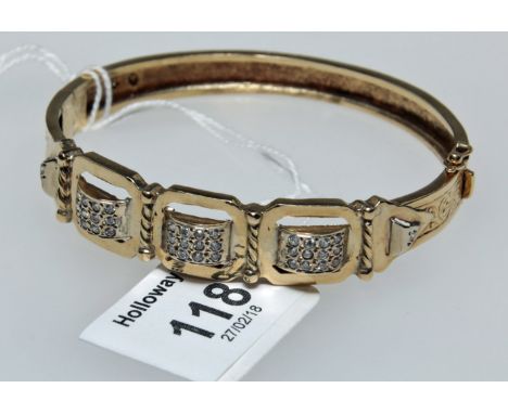 A European bangle, scroll engraved, the centre set with running panels of clear stones, to a push button clasp