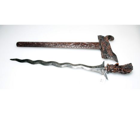 An early 20th century Balinese 'Kris' and scabbard, with heavily carved mythological scenes and Damascind blade, 67cm long, t