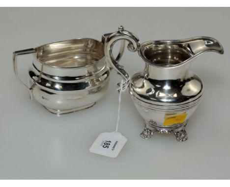 A Victorian cream jug, baluster form, banded to belly, with scrolling handle and four shell-capped bracket feet, London 1843,