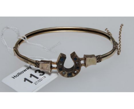 A late Victorian horseshoe bangle, the plain hinged bangle with central horseshoe set with sapphires and rose diamonds