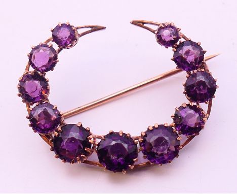 An eleven stone amethyst crescent brooch, circular amethysts 3.5-5.7mm, stamped 333.  3 cm x 2.5 cm.