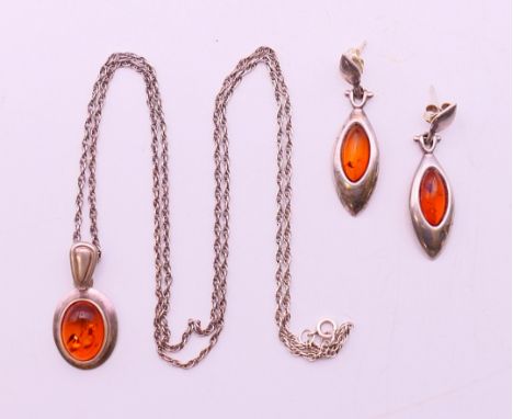 A silver amber jewellery set consisting of an amber and silver pendant on a silver chain and a pair of amber silver earrings.
