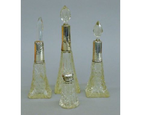 Four silver-topped glass perfume bottles. The largest 18 cm high.