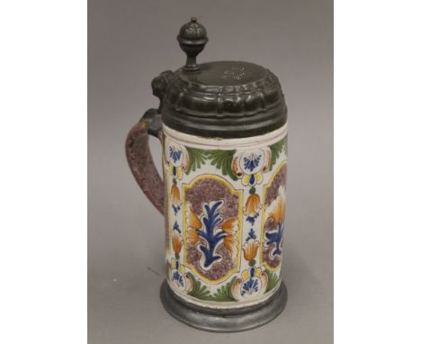 An 18th century Delftware pewter lidded tankard painted in manganese, ochre, green and blue with panels of tulips, the lid in