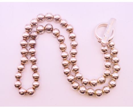 A Tiffany and Co silver bead necklace on hoop and bar clasp, marked '925 T + Co 1837'. 82.4 grammes. 42 cm long.