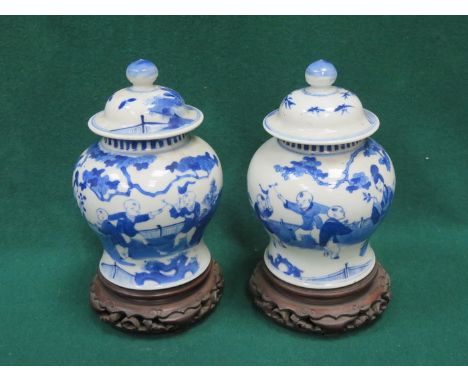 PAIR OF ORIENTAL STYLE BLUE AND WHITE CERAMIC JARS WITH COVERS ON STANDS, APPROXIMATELY 22cm HIGH 