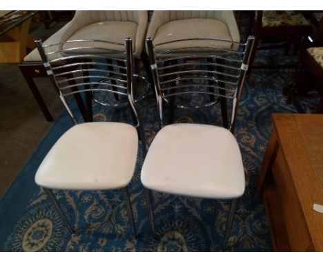 A pair of chrome metal dining chairs with ladder backs and cream leatherette seats 