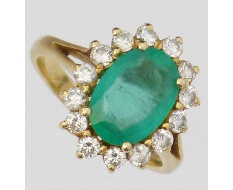 Emerald and diamond oval cluster ring, the central stone 11.45 x 8.06 x 4.35mm, surrounded by round brilliants in 18K mount, 