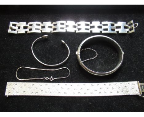 Hallmarked sterling silver bright cut bangle with safety chain, a slim silver bangle with button terminals, a sterling silver