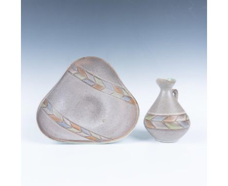 A small jug and triangular bowl in light gray, decorated in a geometric feather-like pattern painted with red, green, blue an