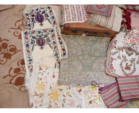 A NEEDLEWORK RUG, OLD EMBROIDERIES together with a collection of textiles and cushions, contained in a vintage suitcase