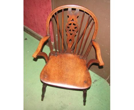 Circa 1860 an elm and oak hoop back Windsor armchair, the stick back with central wheel splat over a dished seat on turned le