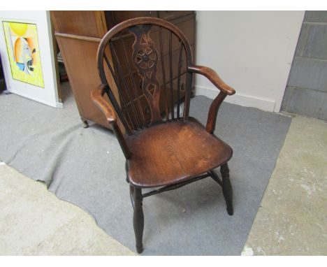 Circa 1860 an elm and oak hoop back Windsor armchair, the stick back with central wheel splat over a dished seat on turned le