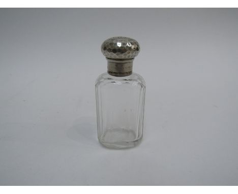 An Edwardian panel-cut clear glass scent bottle with planished silver screw-on top, engraved with initials, the neck engraved