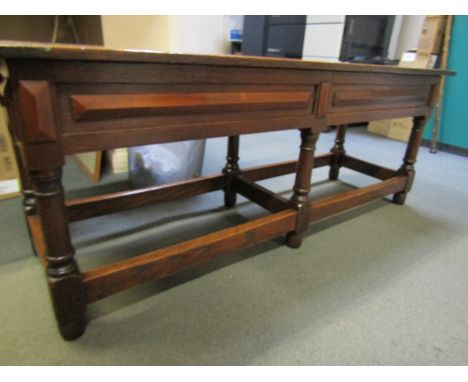 A 17th Century style oak window bench the hinged and cleated end seat over six cannon barrel turned legs joined by stretchers