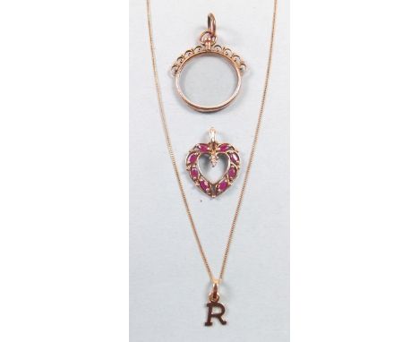 A 9 carat gold pendant set red stones, a gold 'R' pendant and a 9 carat gold framed open locket 