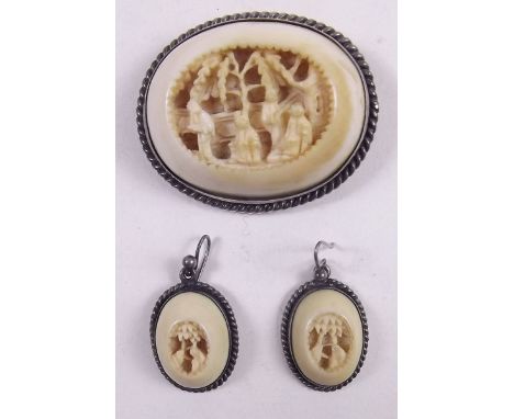 A Victorian silver mounted oval ivory brooch and earrings carved figures and landscapes 