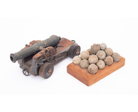 A small group of grape or musket shot on a later wooden base, together with small model cannon.