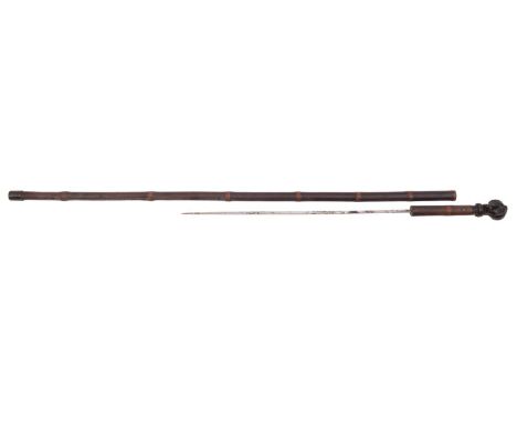 A 19th Century carved horn customs stick, the square section spike within a bamboo case with carved horn pommel in the form o