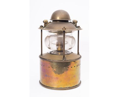 A circular brass toplght, unsigned, the domed cover with swing handle above, clear glass lens enclosing spring loaded candle 