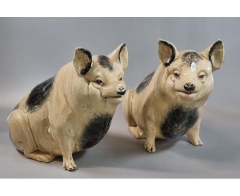 Pair of pottery seated Wemyss style pigs.  19.5cm high approx.  (2)   (B.P. 21% + VAT) One of the pigs has lost his front foo