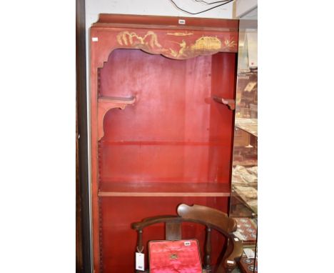 An Oriental red japanned open bookcase,early 20th century, the caddy top over a shaped frieze decorated with chinoiserie land