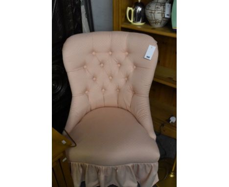 A pink upholstered button back bedroom chair.