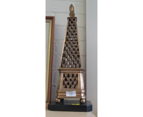 An Indian brass obelisk, of traditional pierced form with flame finial on a slate plinth