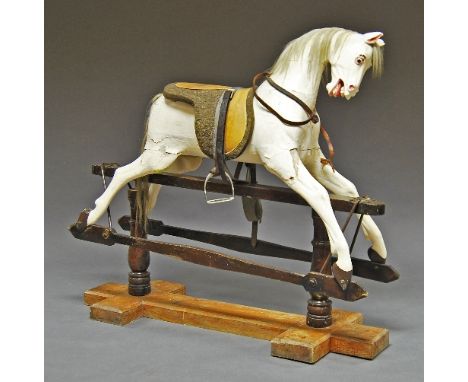 A large wooden rocking horse, late 19th/20th century, painted white and mounted on a wooden stand, with replacement saddle, 1